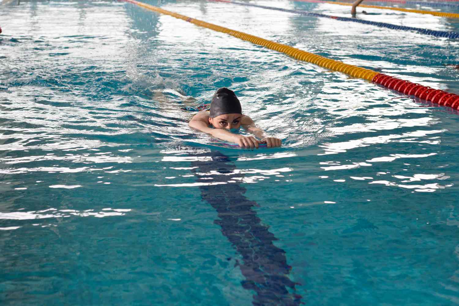 A young girl swims in the pool with a supporting Board for practicing smooth movement on the surface of the track.