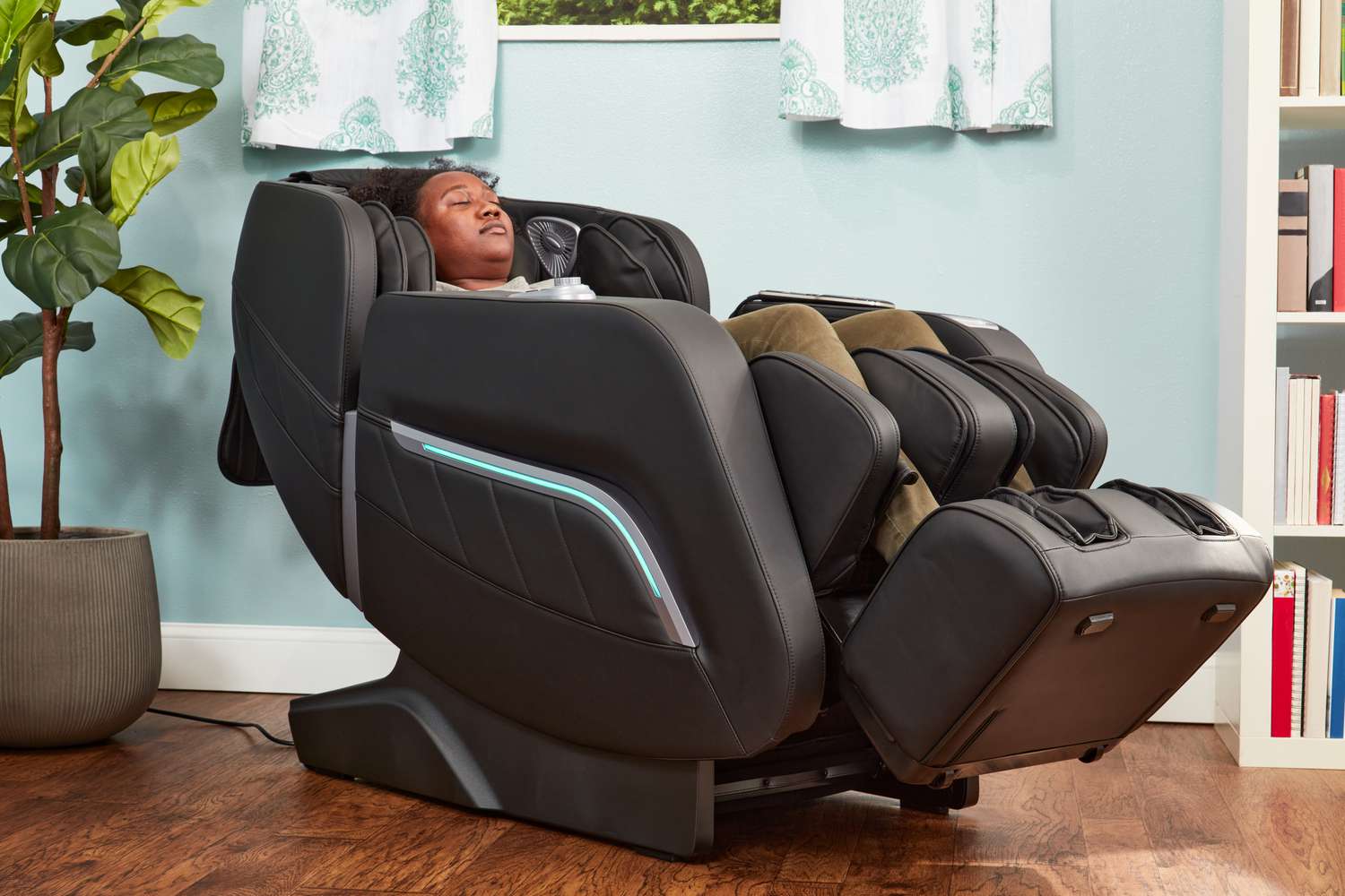 A person reclines in an iRest Zero Gravity Massage Chair in a blue room
