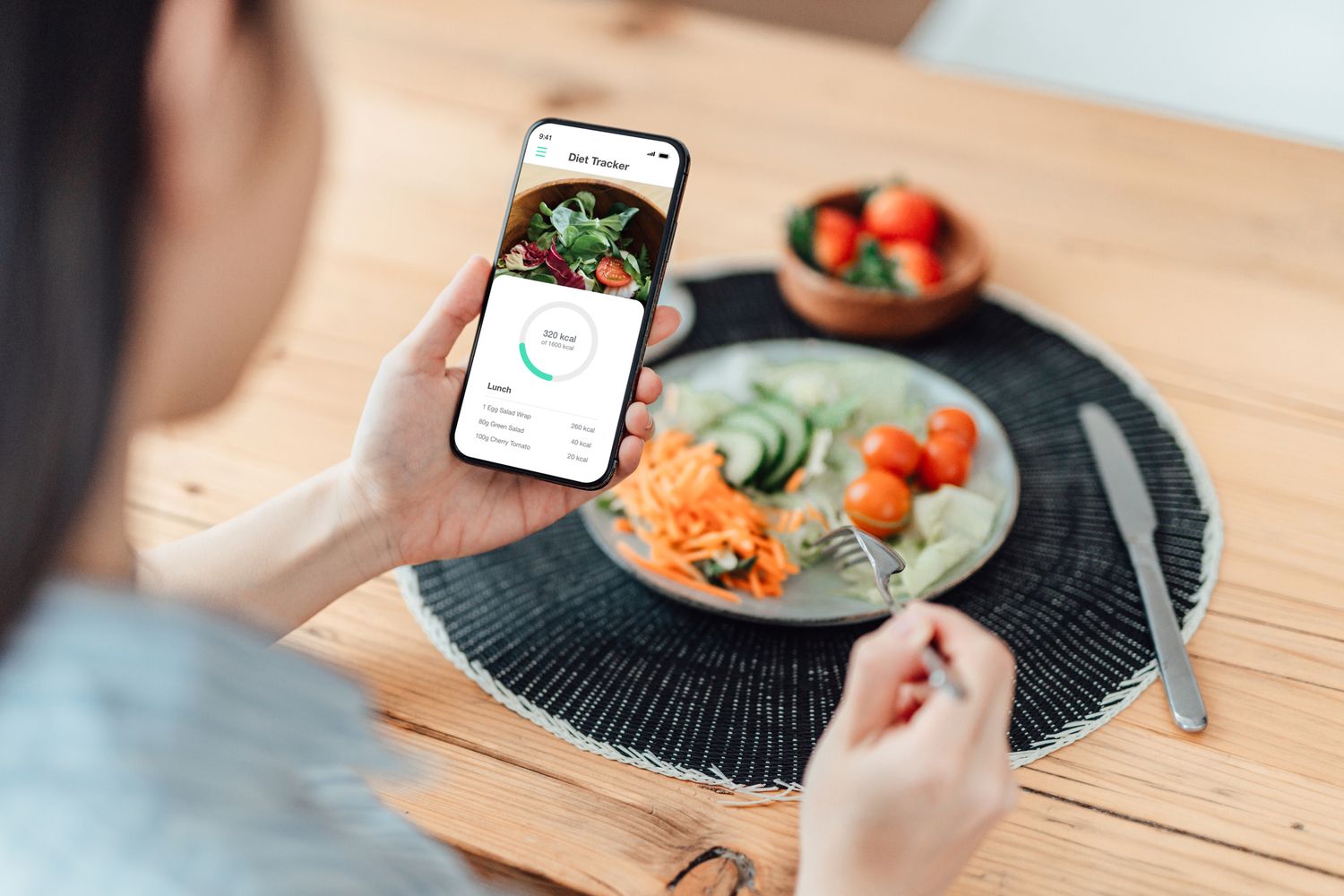 woman tracking calories with an app and eating lunch