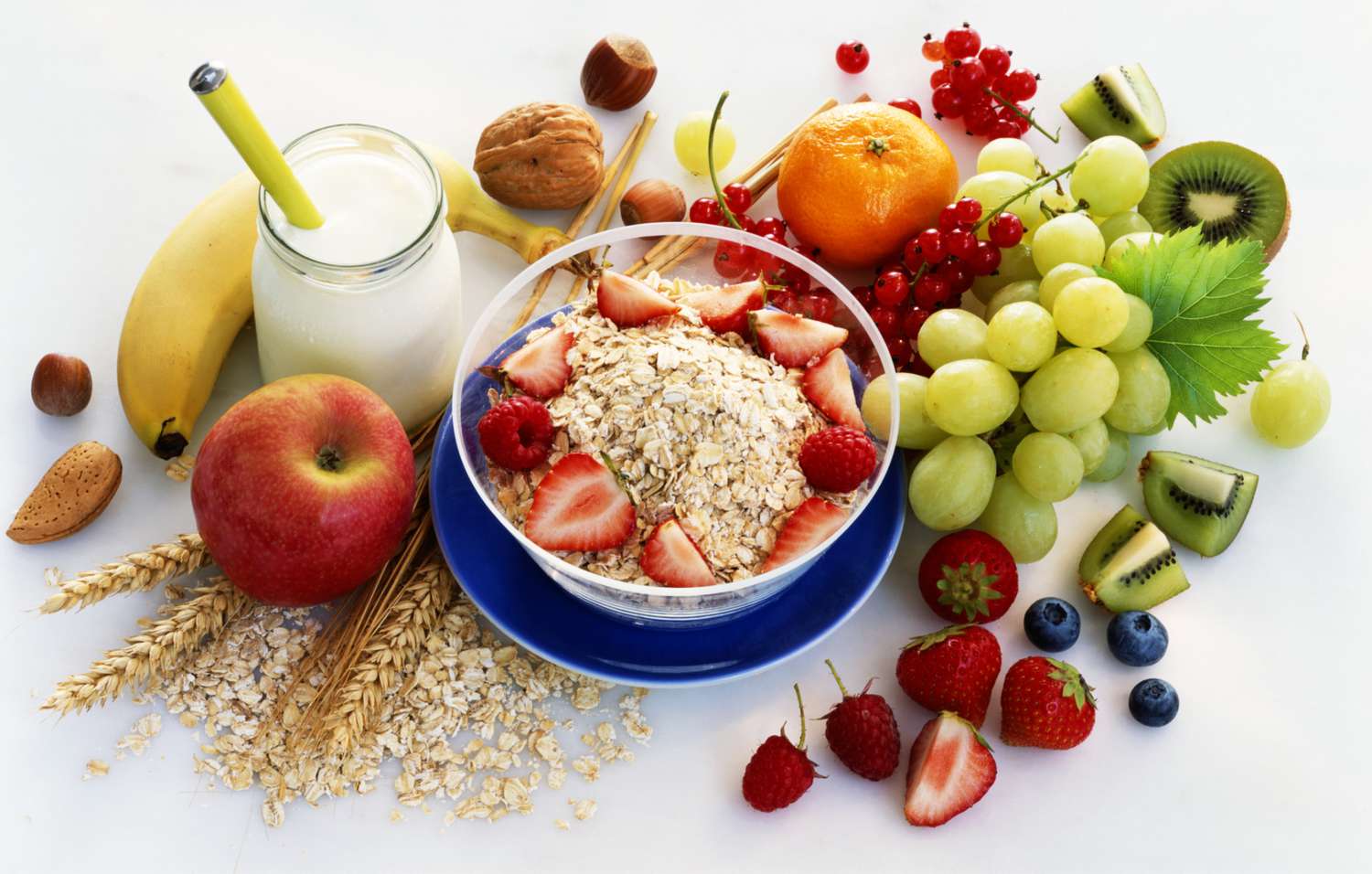 healthy breakfast foods, including fruit and oatmeal, on a white tabletop