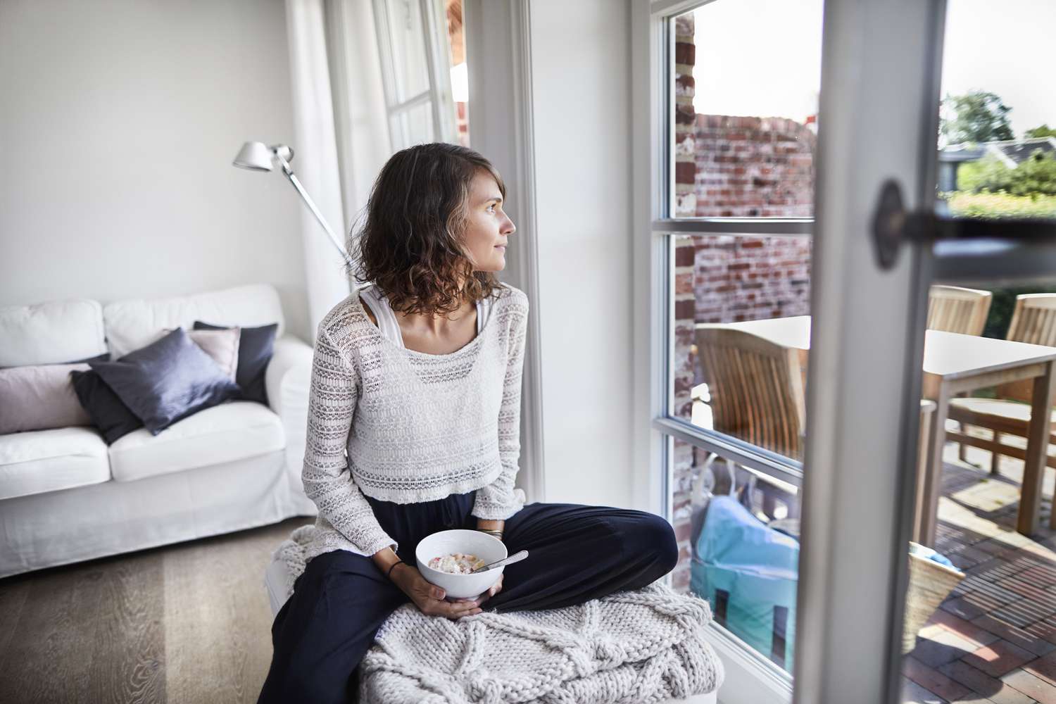 Woman looking out the window as she eats her breakfast