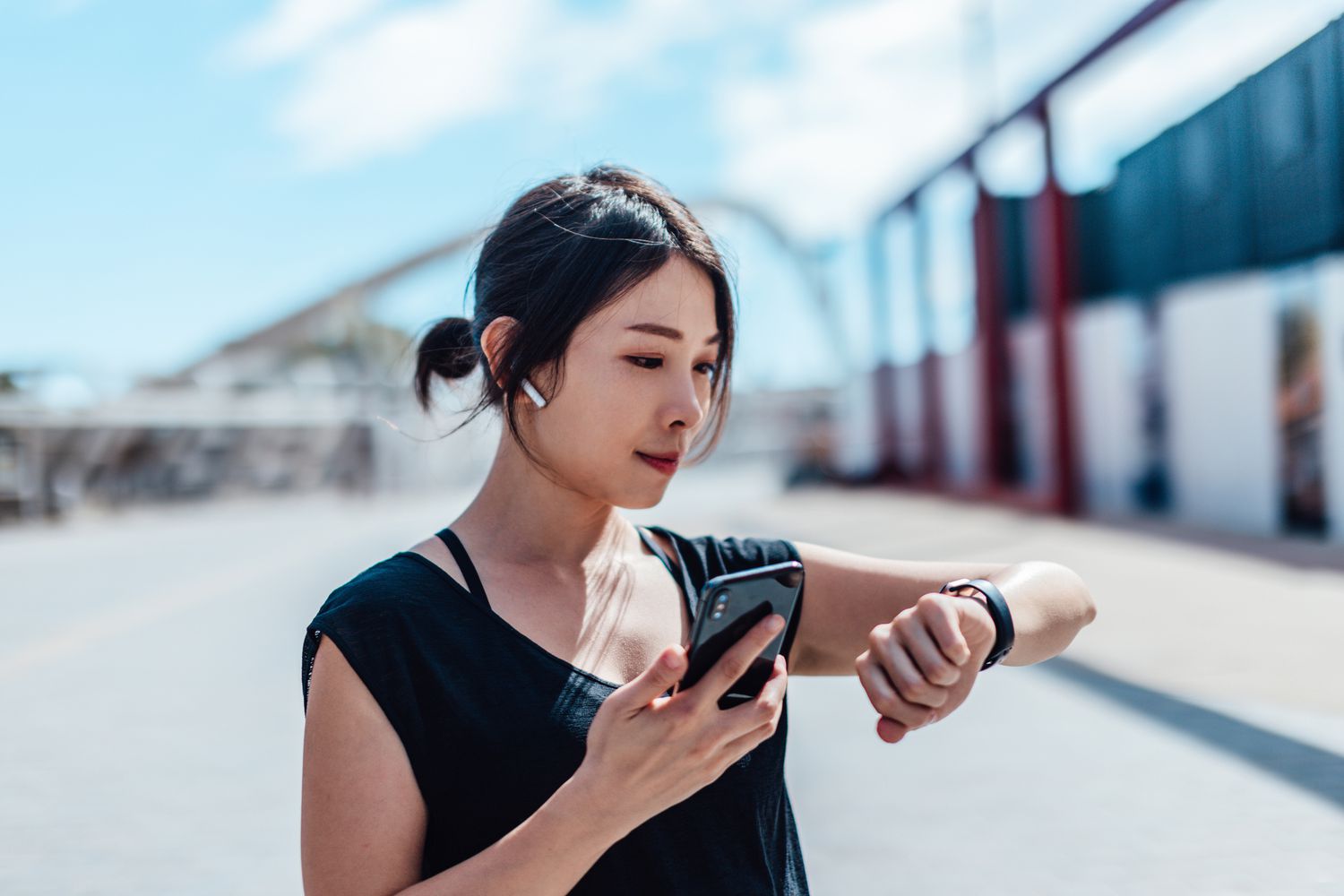 Young women wearing earbuds and holding phone