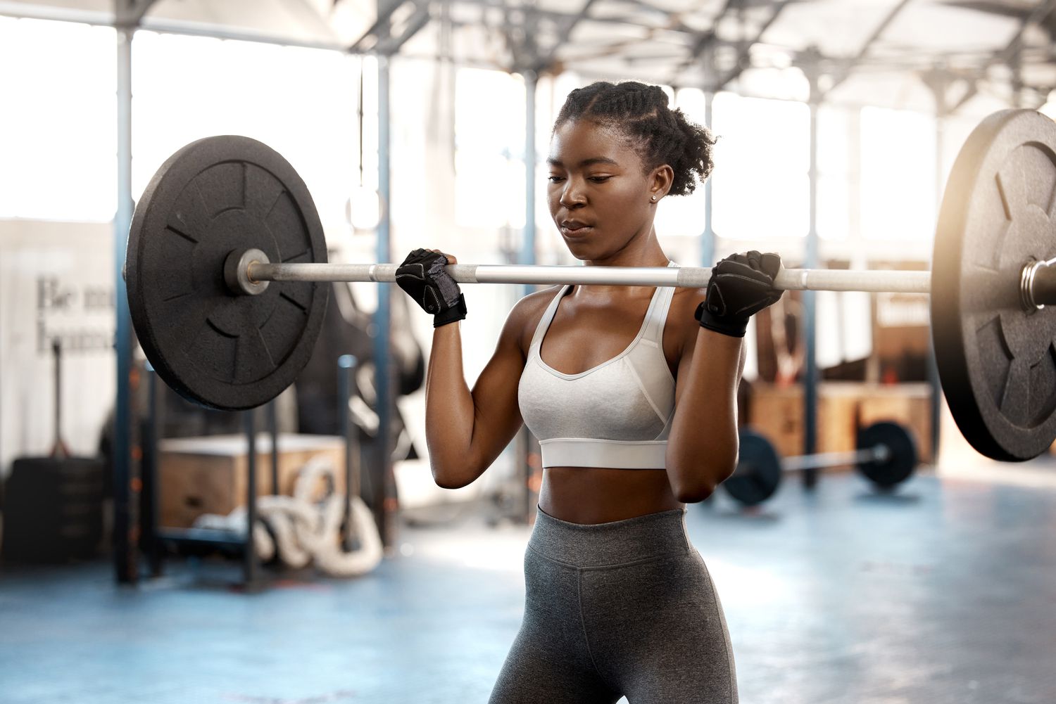 Shot of a sporty young woman exercising with a barbell in a gym