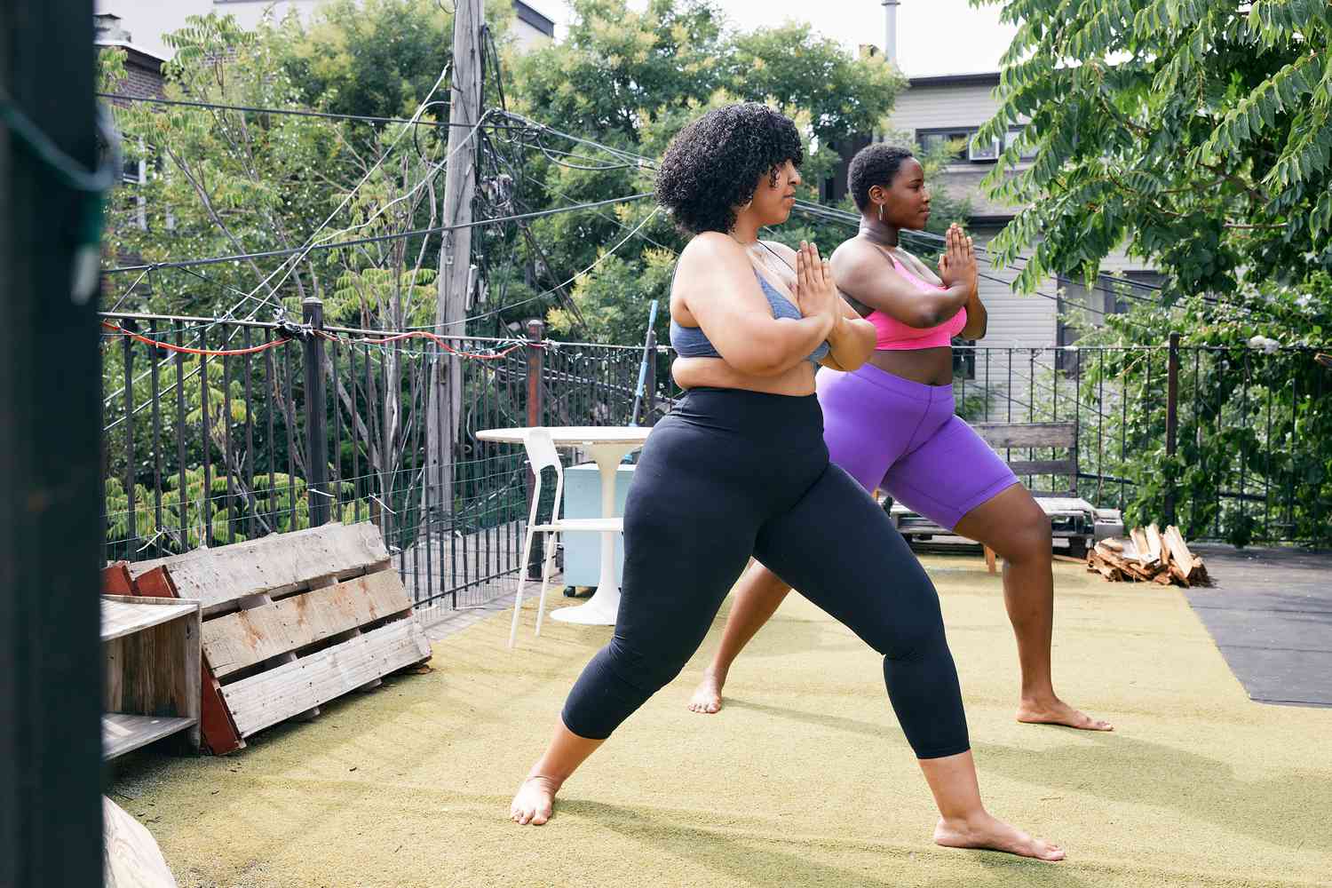 two women doing yoga outside; Two body positive women practicing yoga together 