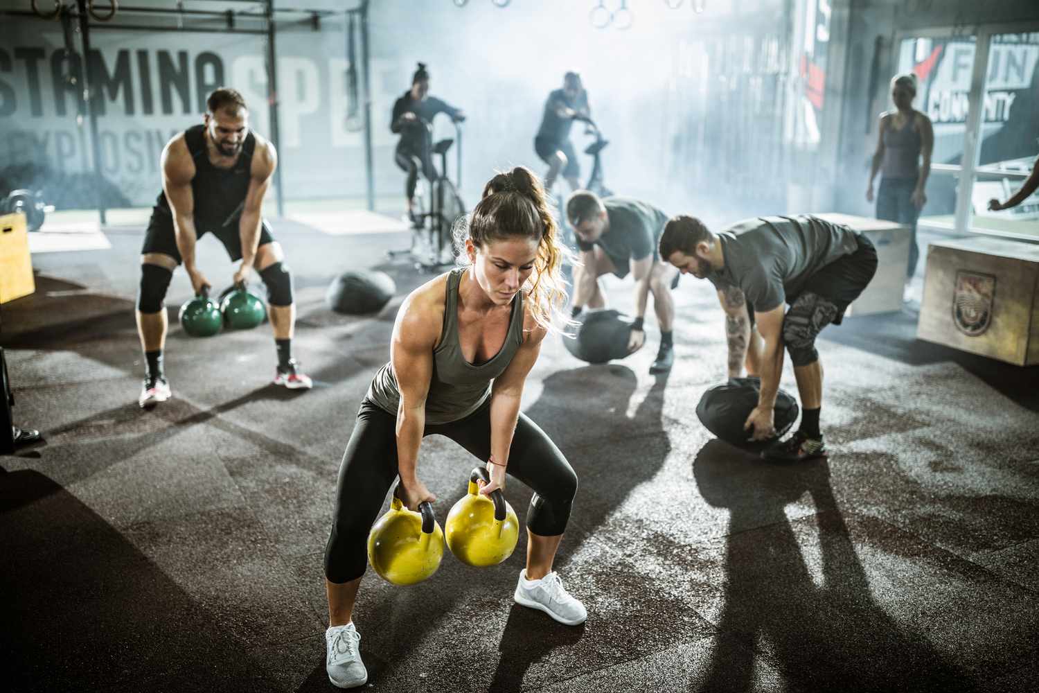 People performing workouts in gym group setting with kettlebells