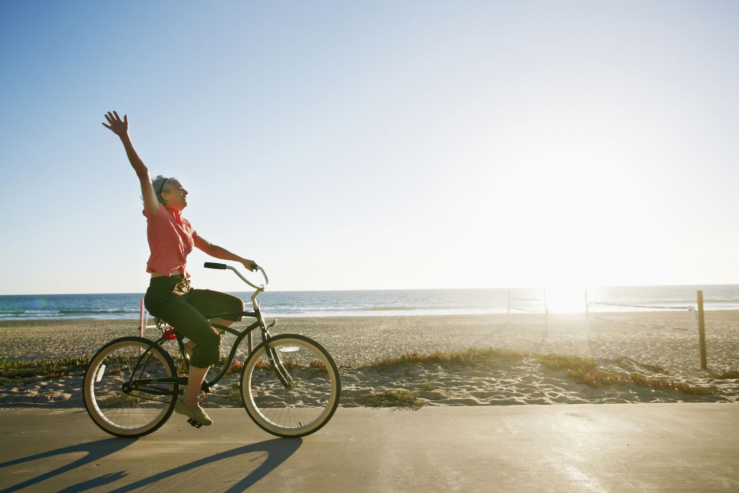 Woman riding bicycle on path in front of beach