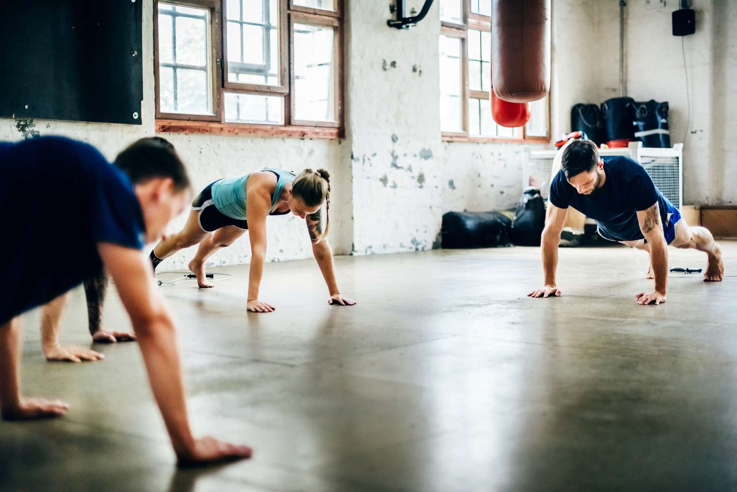 Three CrossFit athletes performing push-ups in a CrossFit gym.