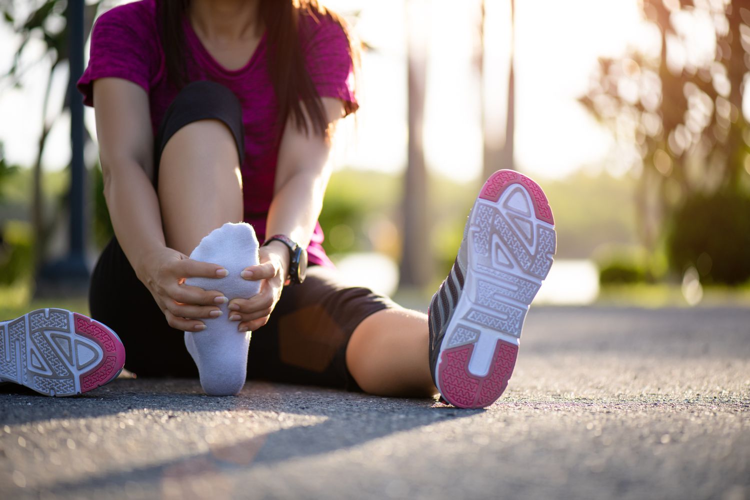 Young woman massaging her painful foot while exercising. Running Sport and exercise injury concept.