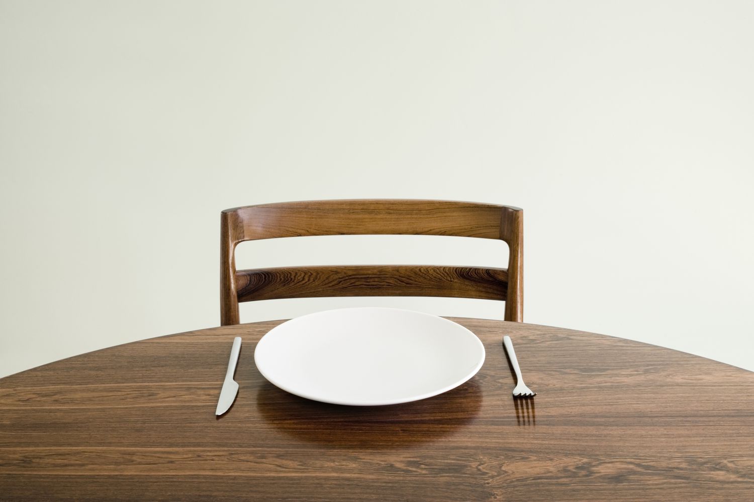 Empty plate with knife and fork on table.