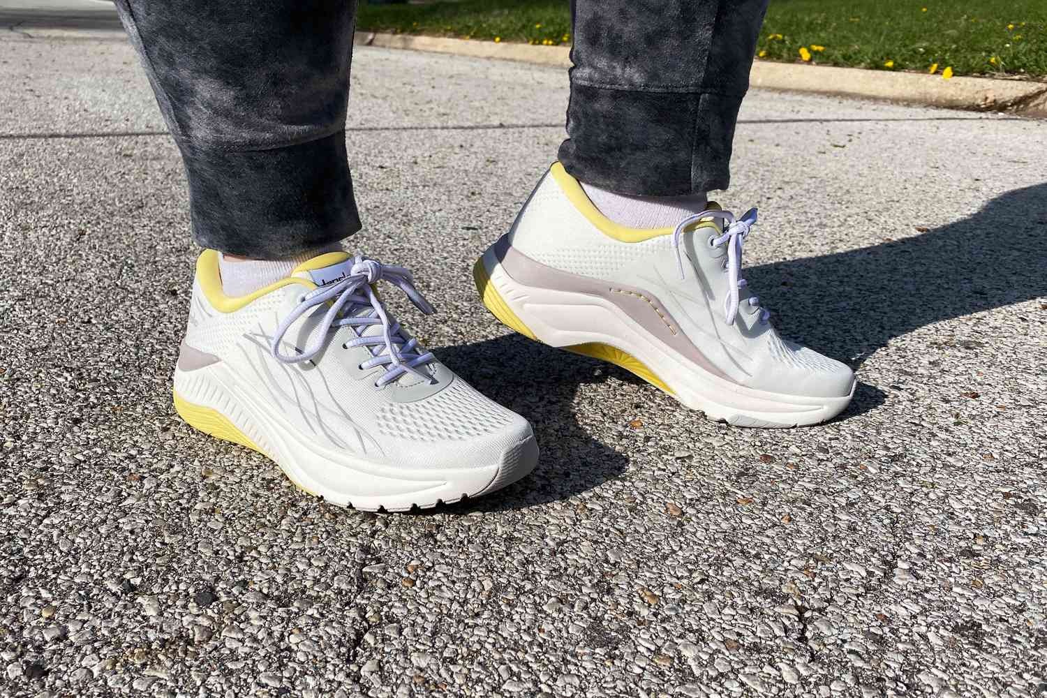 Feet wearing Dansko Women's Pace Walking Shoes on a paved surface