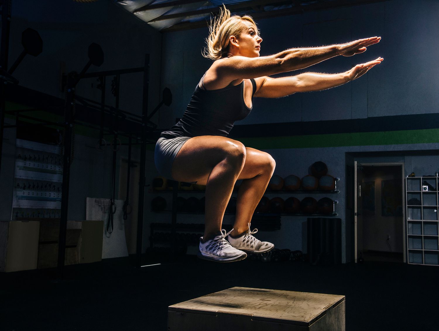 Woman jumping onto a box in the gym