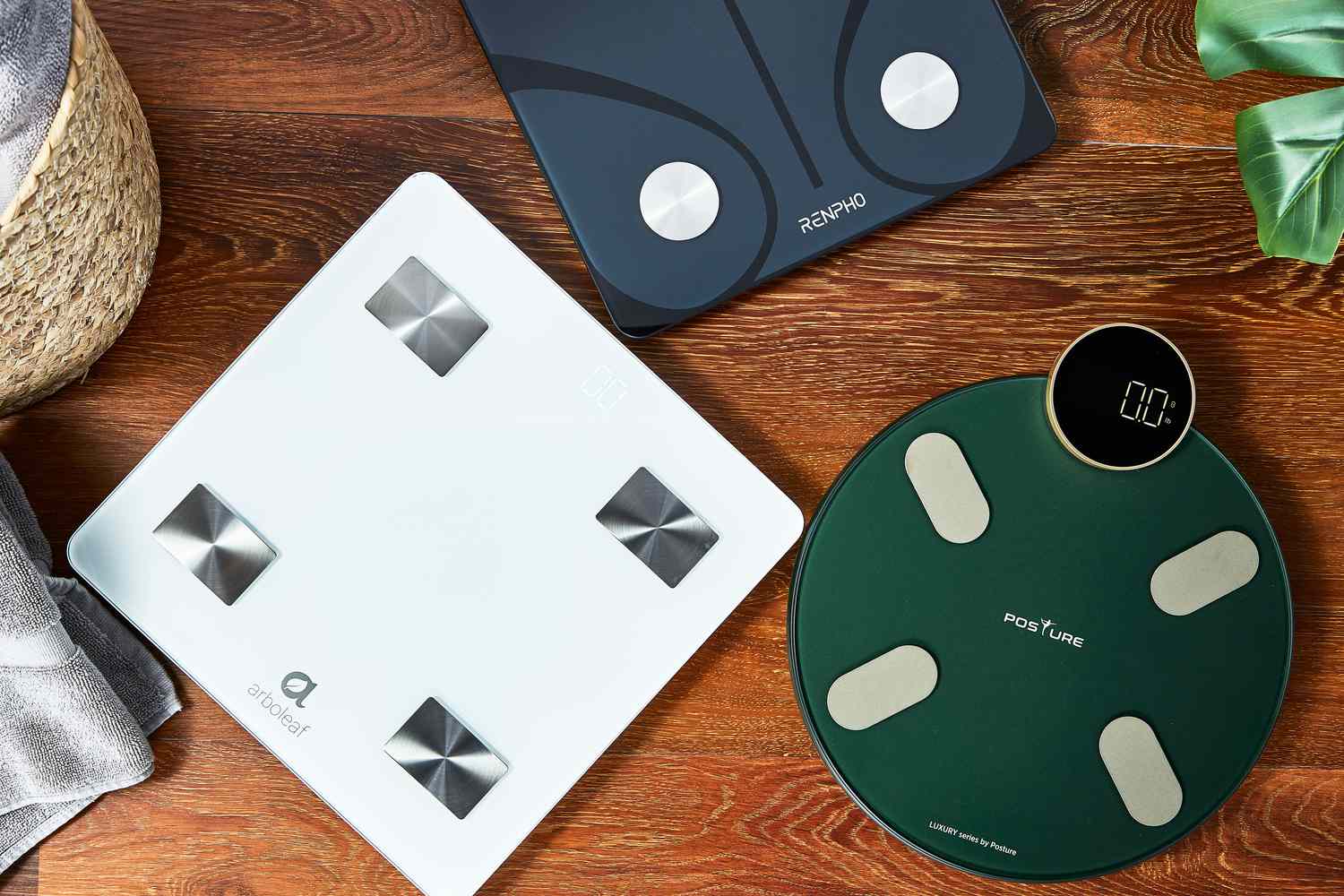 An assortment of smart scales we recommend on a wood floor
