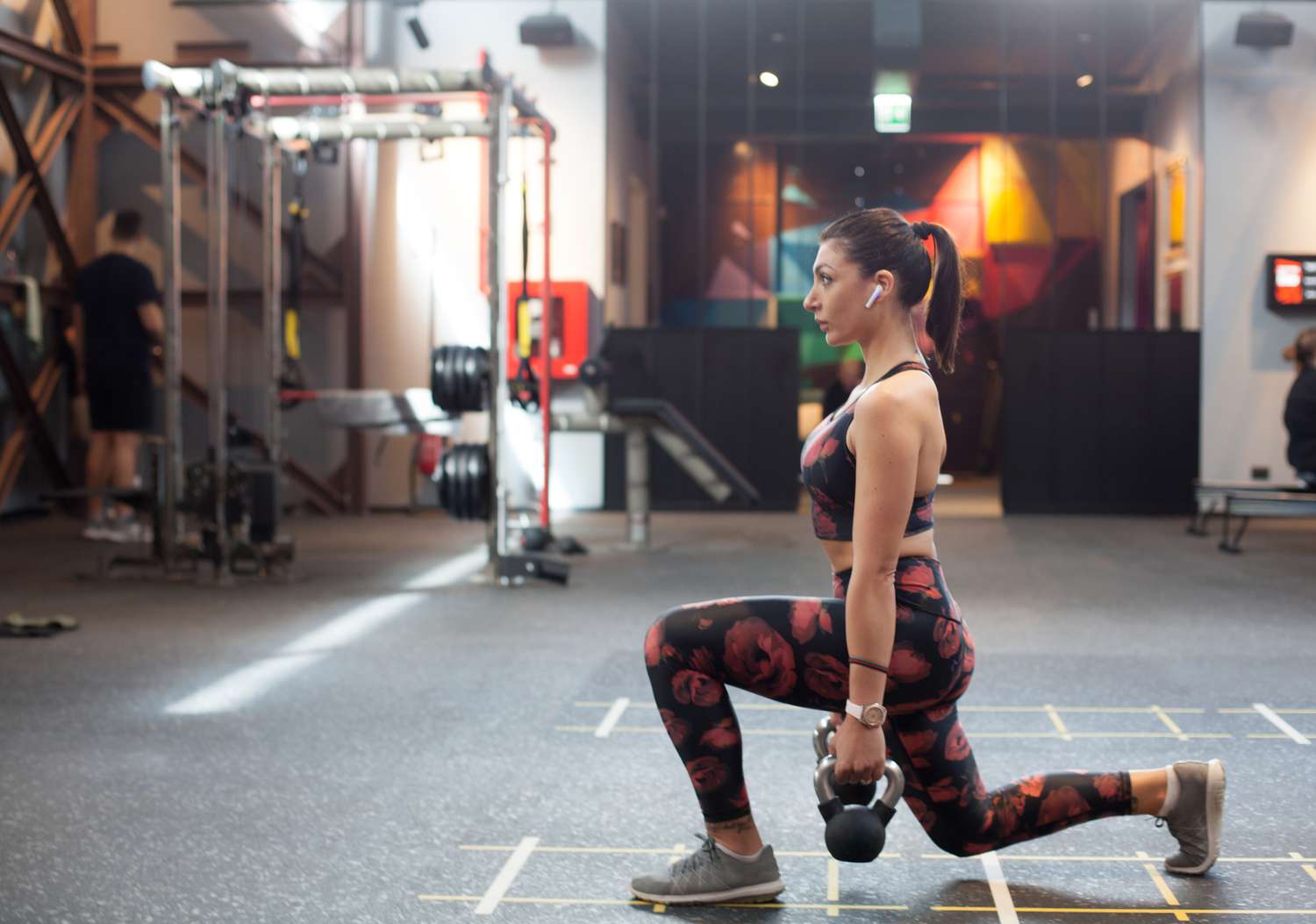 woman lunging with kettlebells at gym