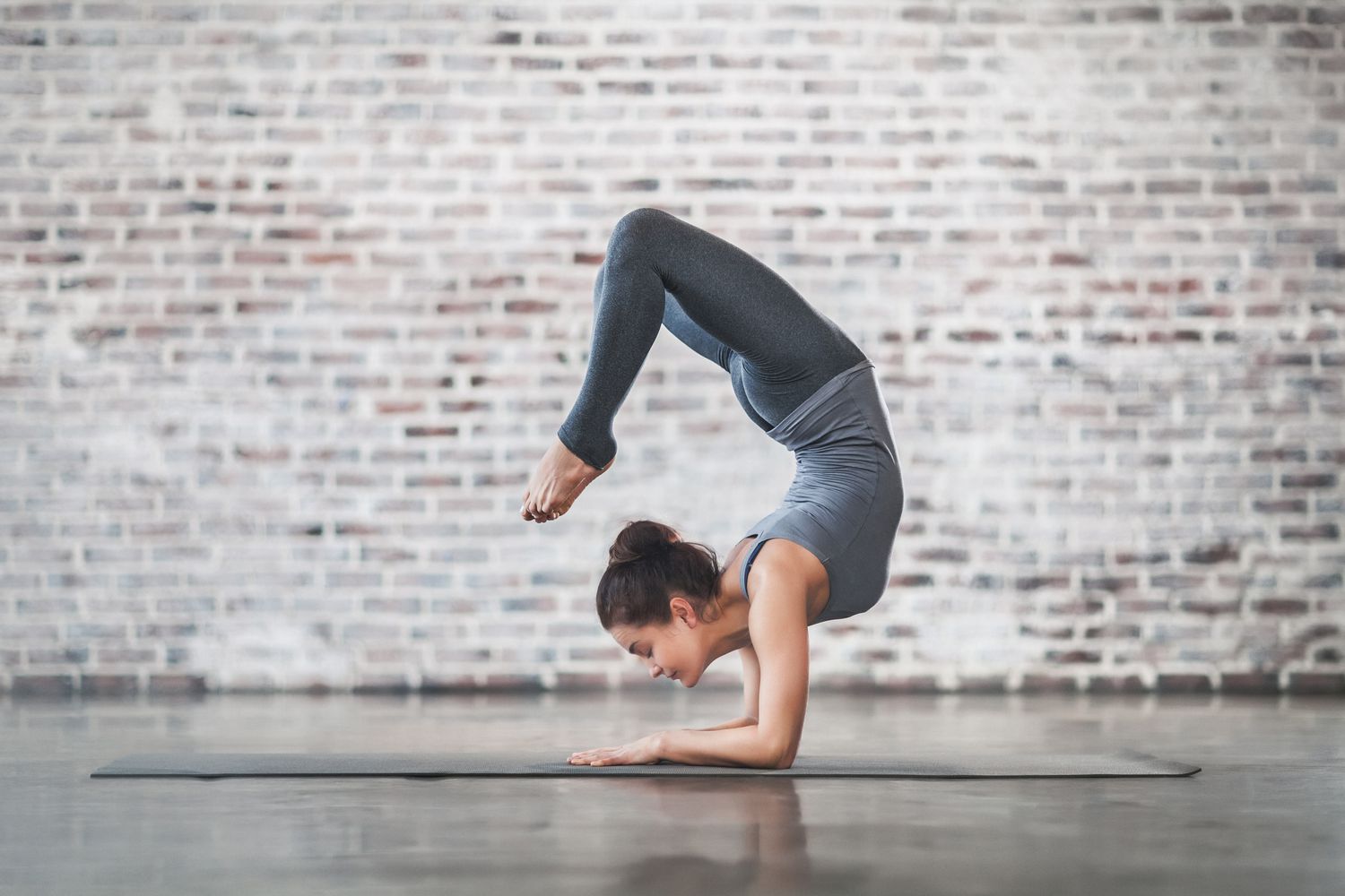 Woman in scorpion pose on yoga mat
