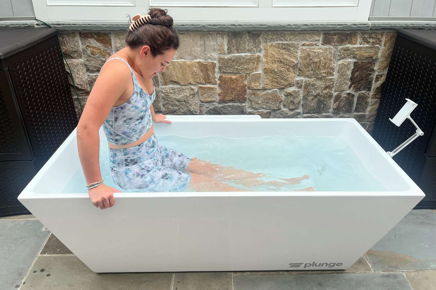 A person lowers themselves into the PLUNGE Cold Plunge Tub