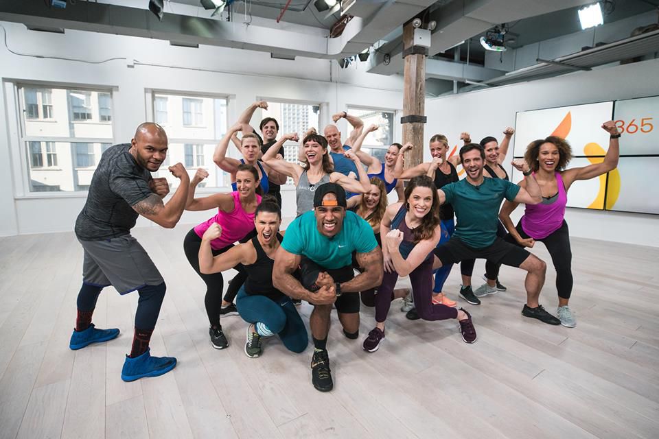 Group of Daily Burn trainers flexing muscles and smiling