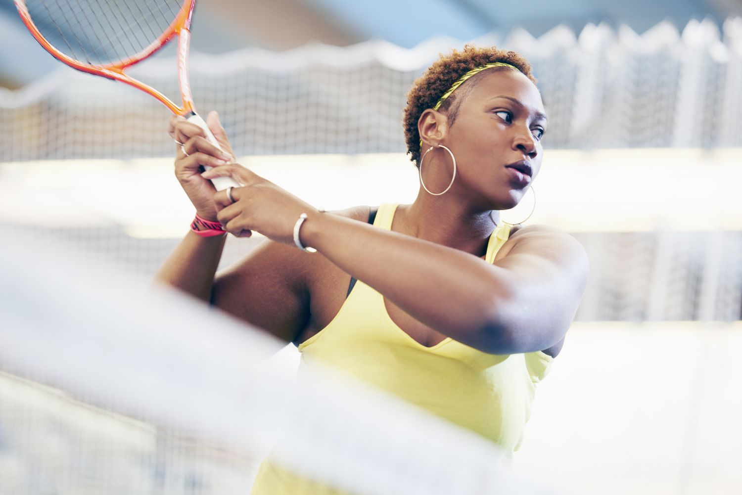 Sports woman on tennis court swinging racket