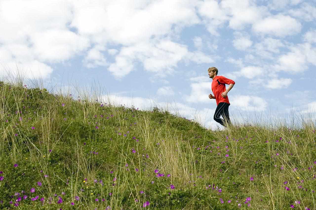 Man running up grassy hillside