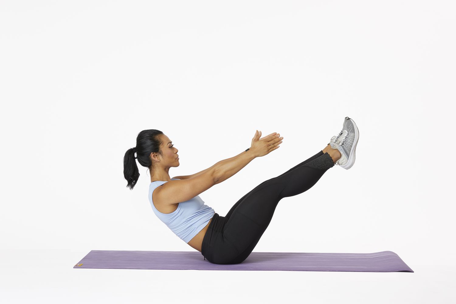 Woman on yoga mat doing a v-sit exercise