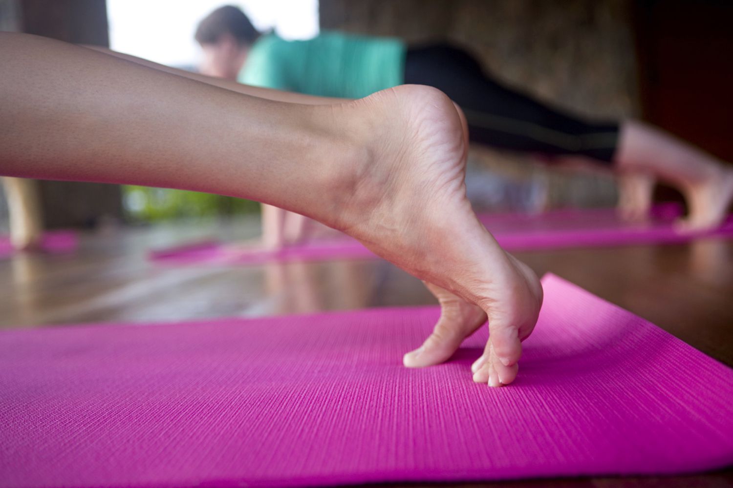 Feet of woman doing a plank on a yoga mat