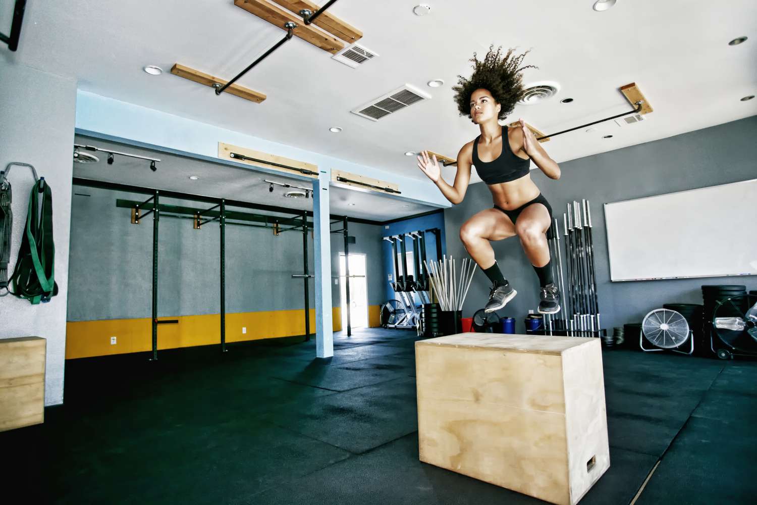 woman doing plyometric box jump exercise in gym