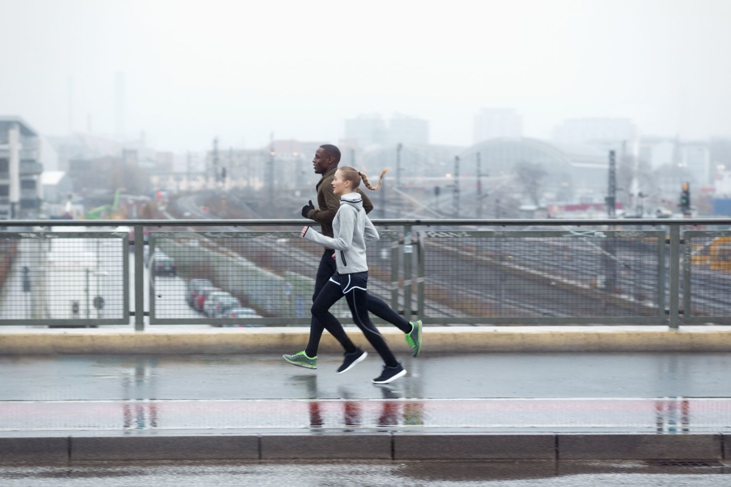 Two friends jogging across urban street bridge