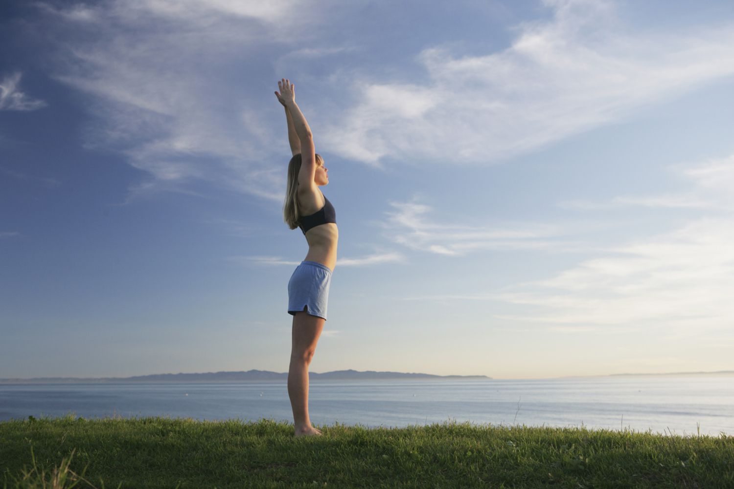 Woman doing yoga on a grassy bluff