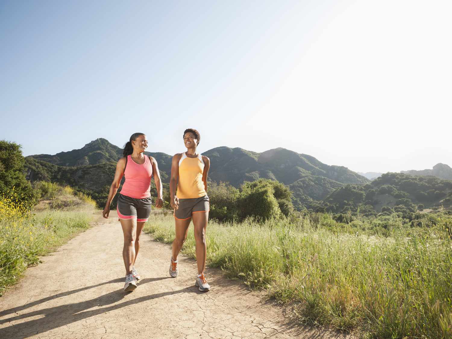 Two athletic people walking outside together on a trail