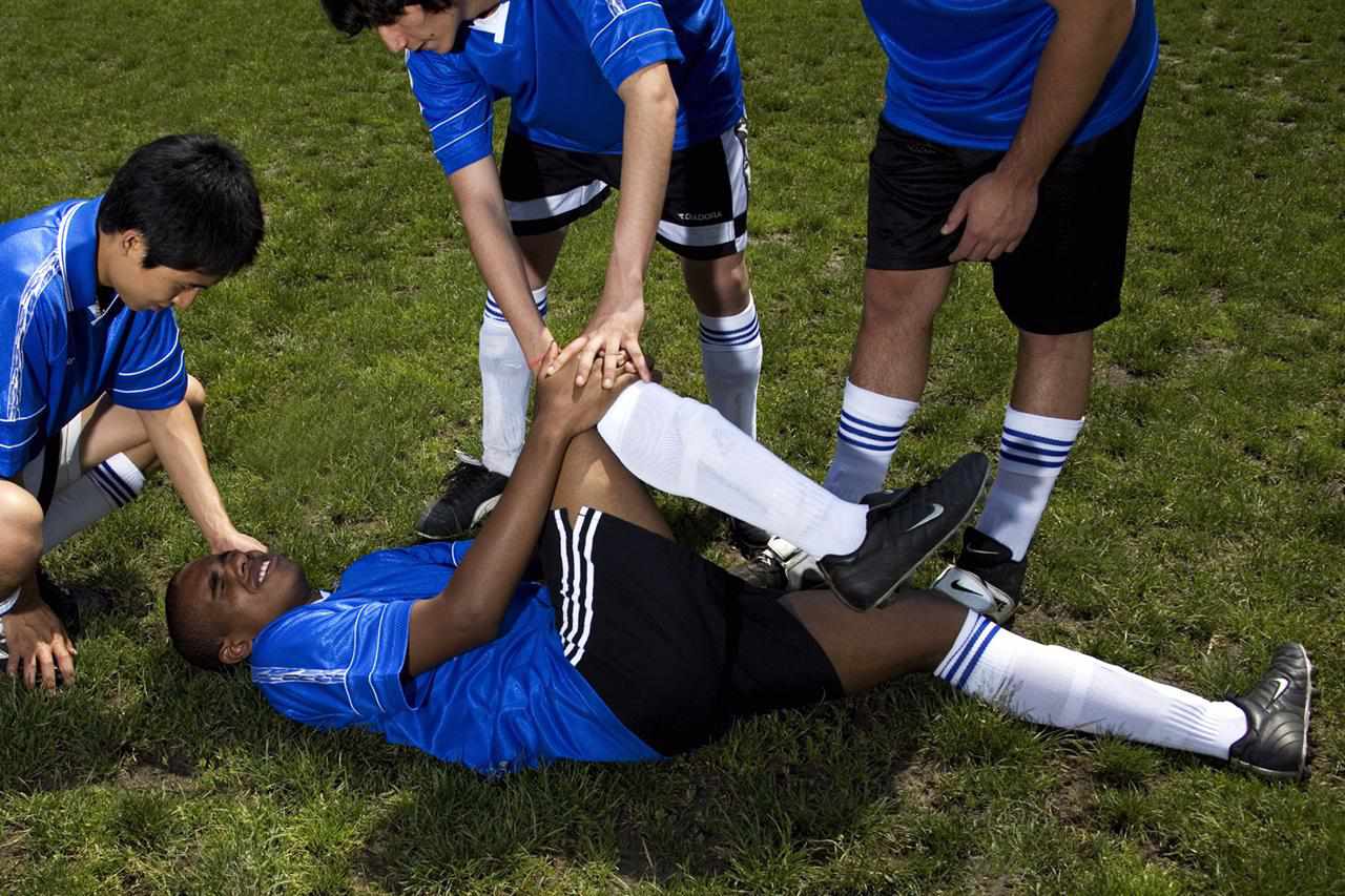Soccer player down on the field holding his knee in pain