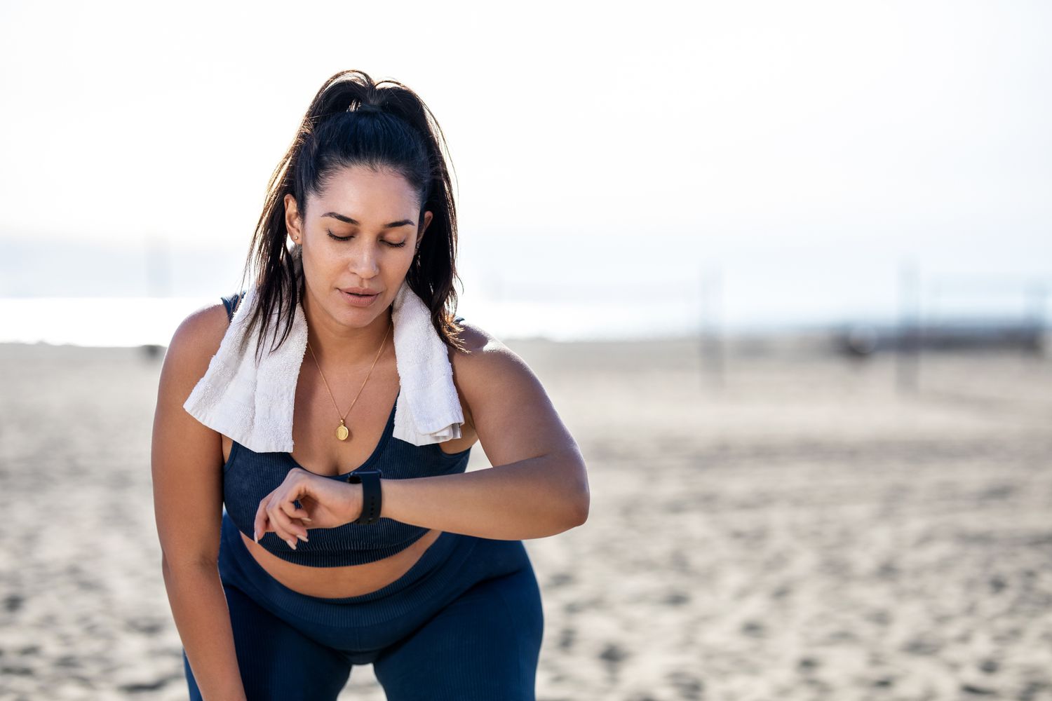 woman checking fitness watch while working out on beach