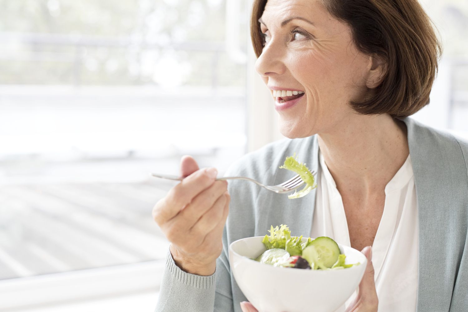 Woman eating a salad, looking out the window