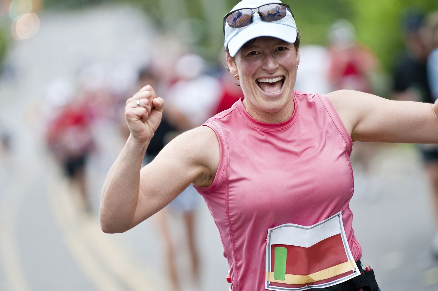Woman smiles broadly and pumps her fists in celebration having completed first 30 of 42 kilometers in her first marathon race.