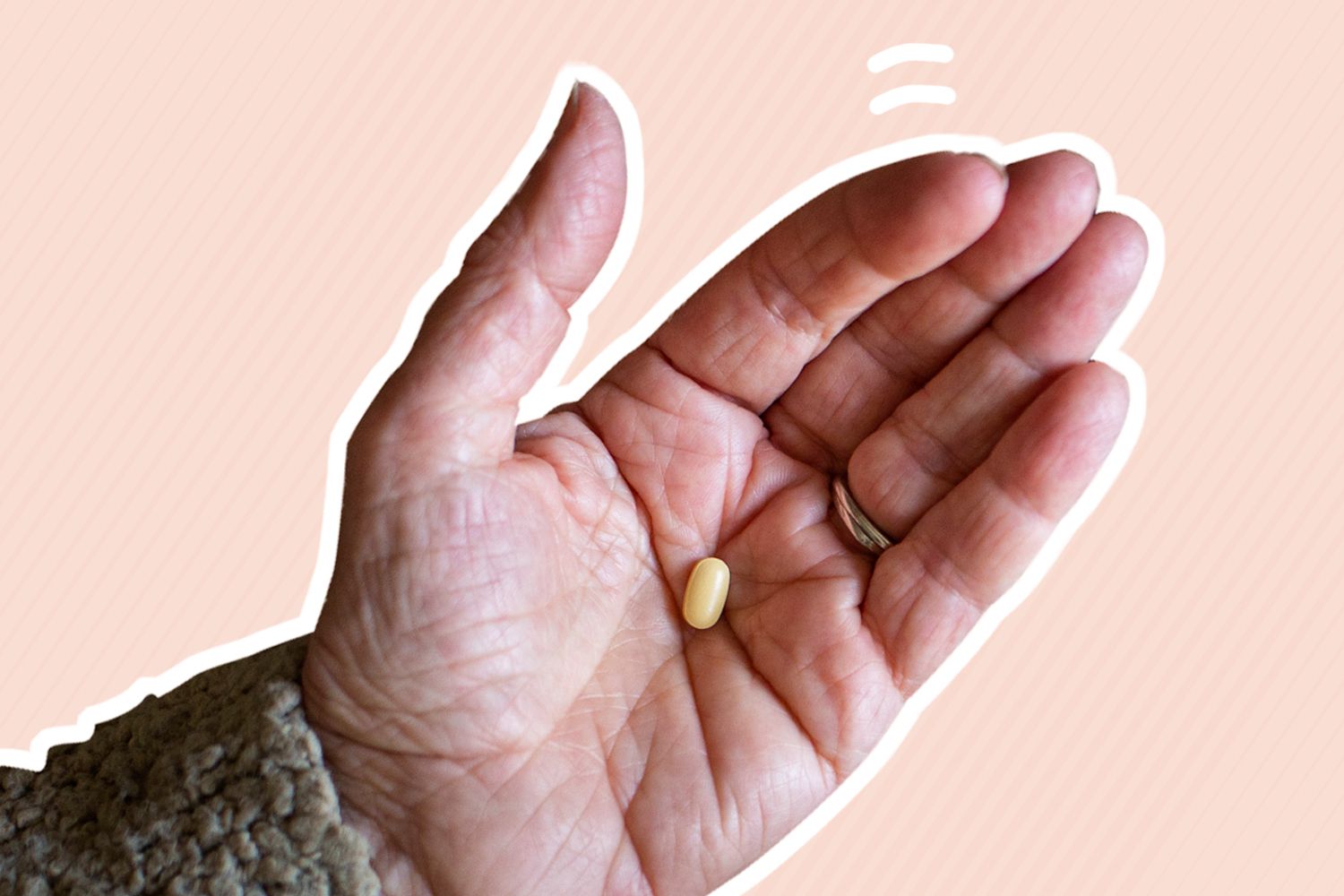 A hand holding a multivitamin for women over 50 on an orange background