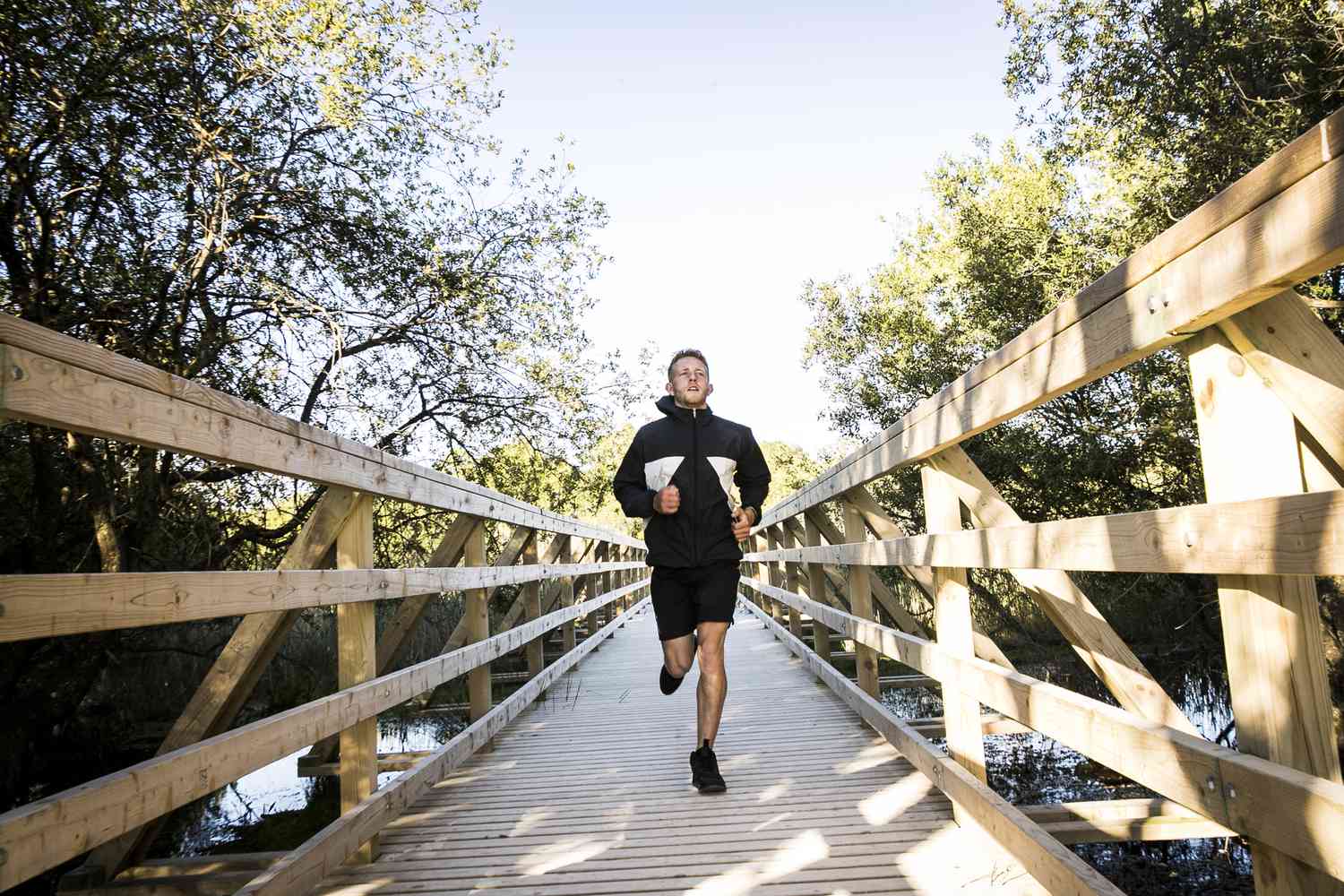 Young male runner running across rural footbridge