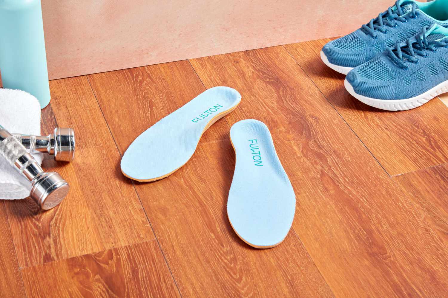 Fulton The Athletic Insoles displayed on a wooden floor with sneakers and dumbbells