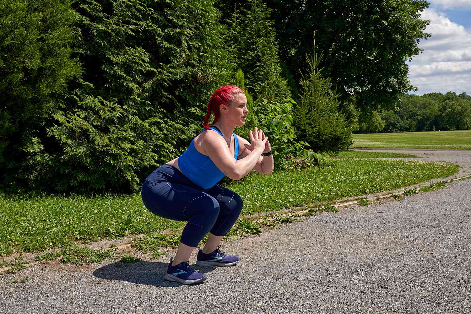woman doing squats on a paved path in a park