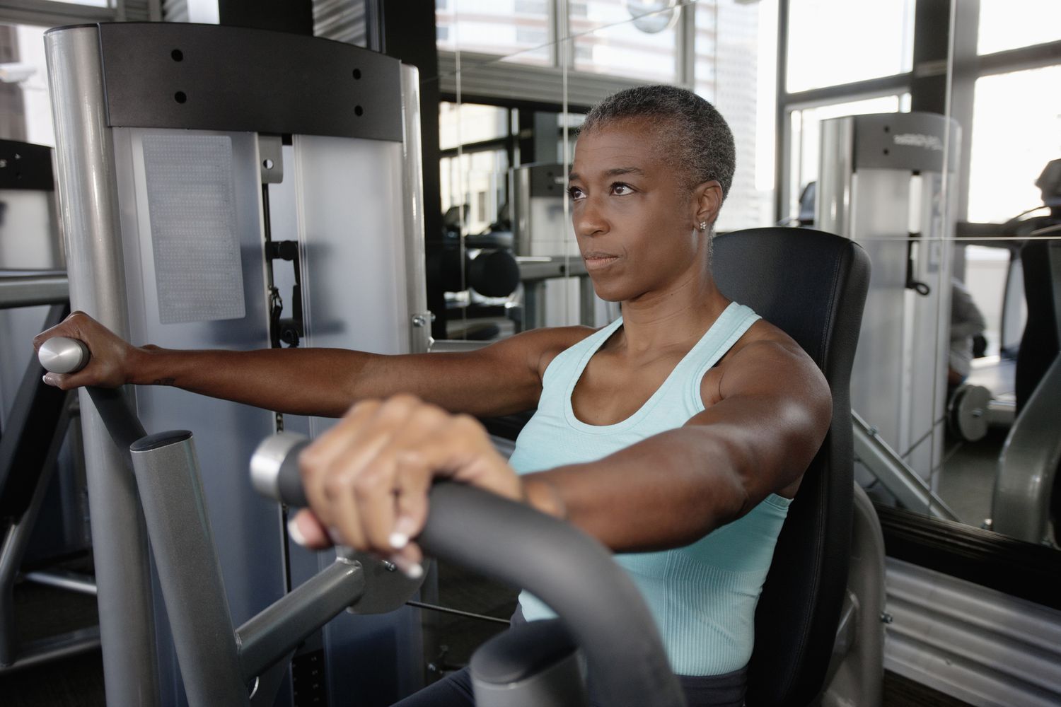 A woman using a chest press machine in a gym