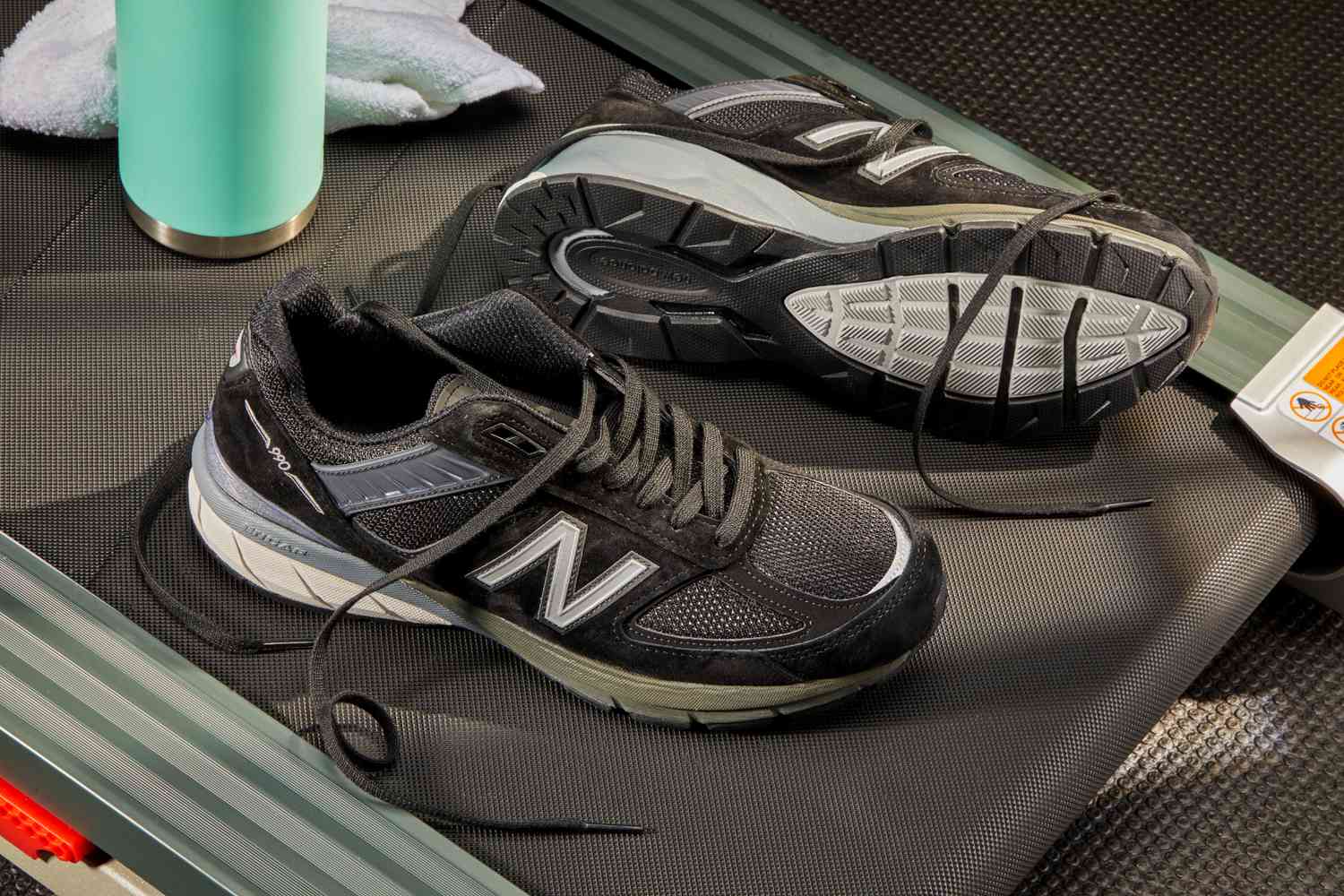 New Balance Men’s M990v5 Running Shoes displayed on the end of a treadmill