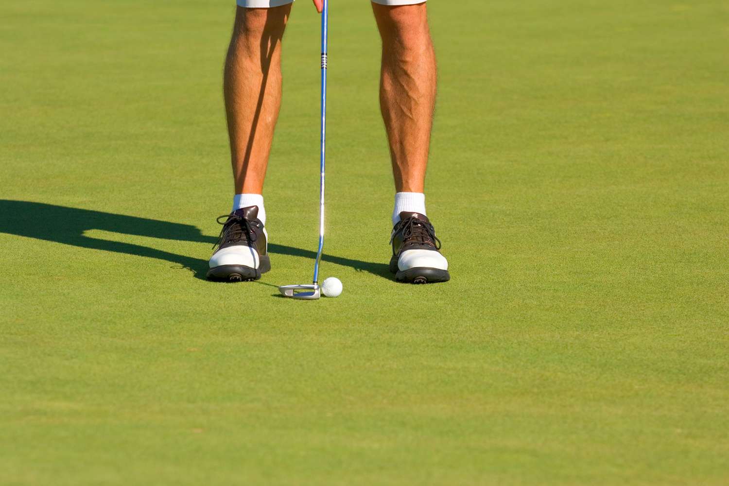view of man's leg putting on golf course