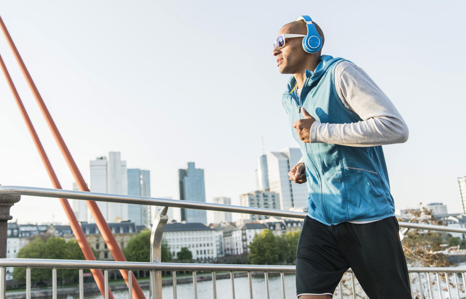 Germany, Frankfurt, man wearing headphones jogging on bridge