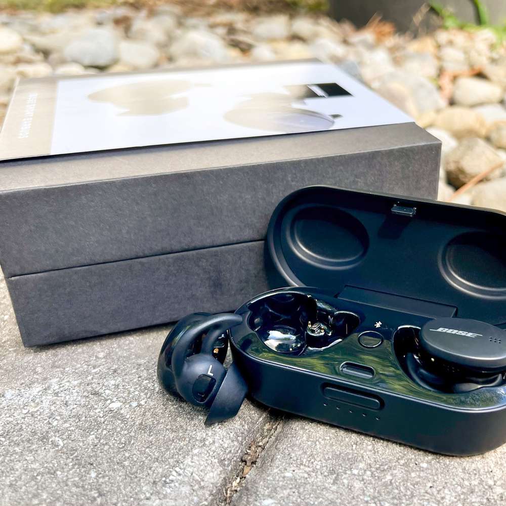 Bose Sport Earbuds displayed with box on path next to gravel