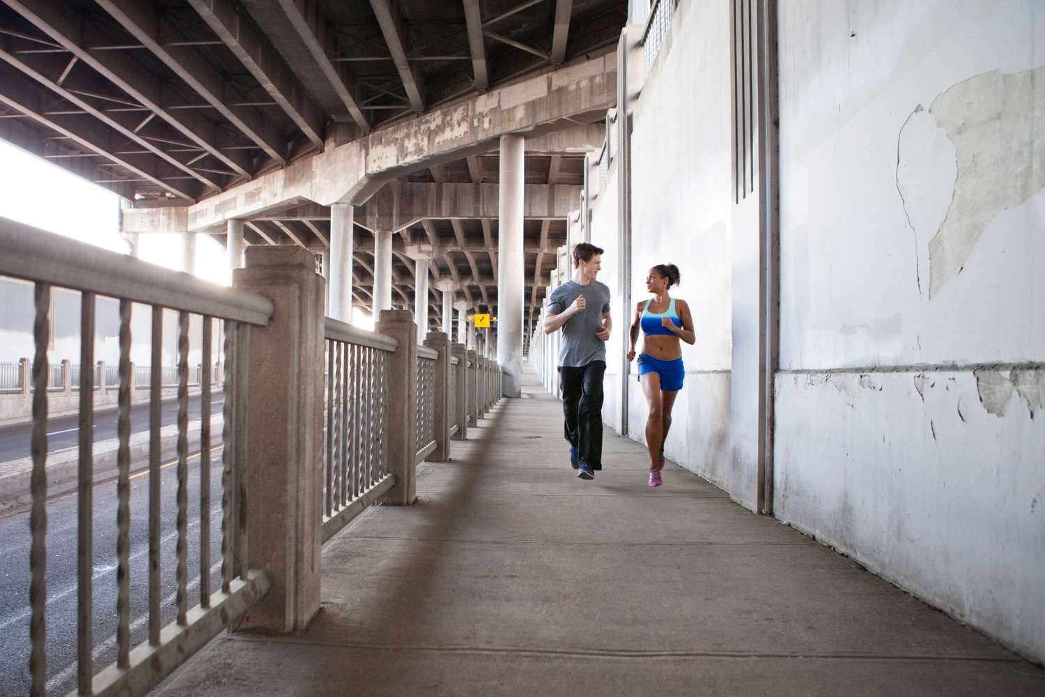Young couple running on city bridge