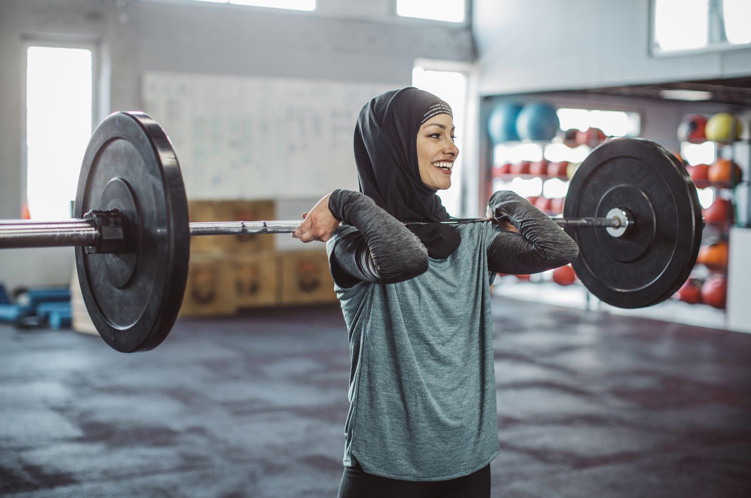 Young woman on cross training weightlifting. Wearing sports clothing and hijab.