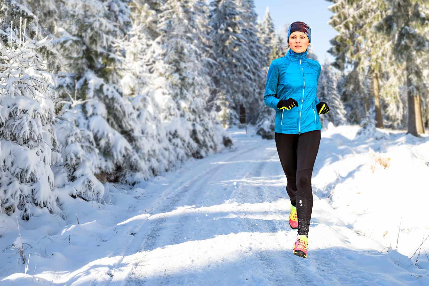 Woman running outdoors in cold weather on snowy path
